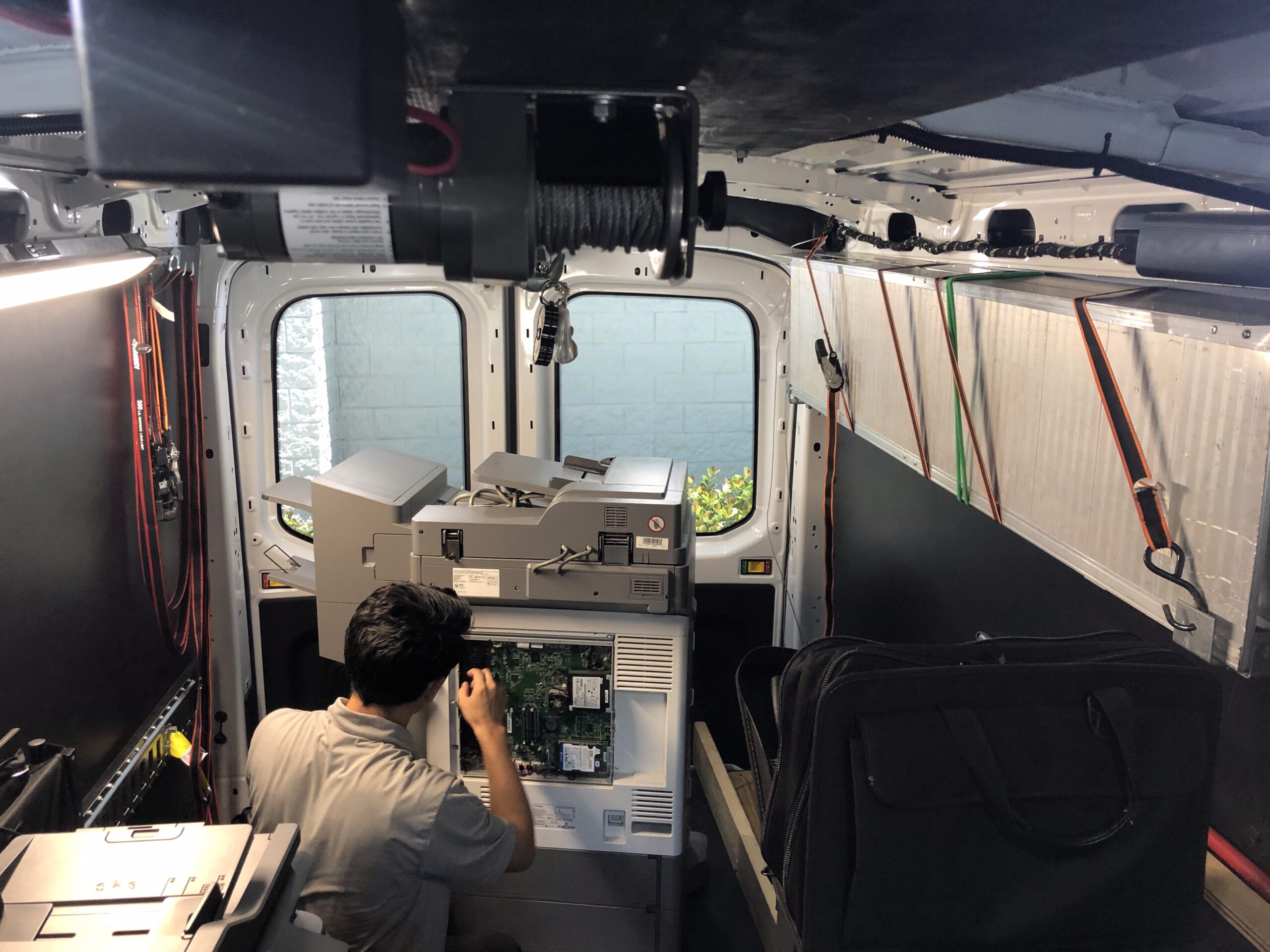 Lexmark technician working on a printer inside his company van